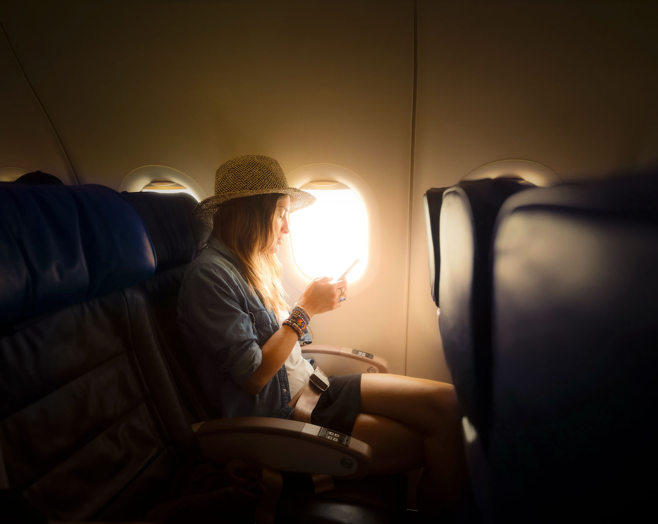 Female traveller using mobile phone on a flight
