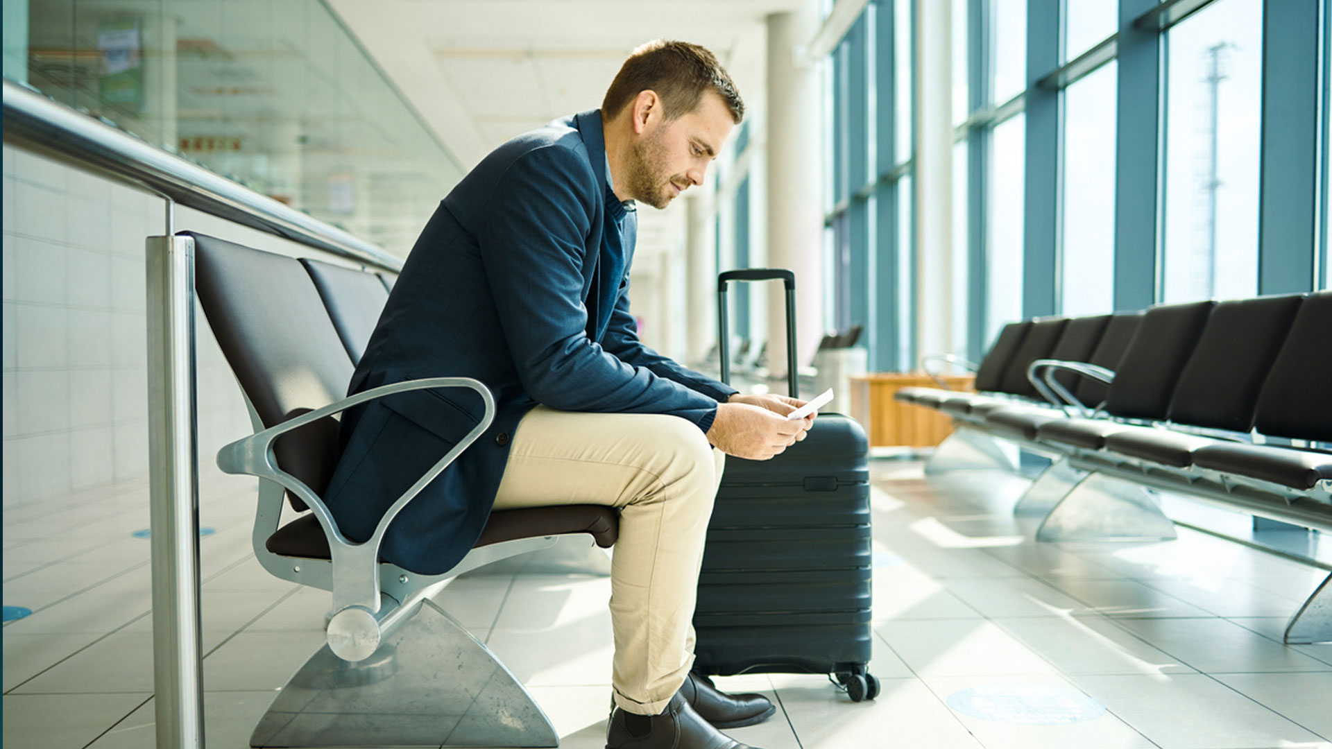 Traveller using his phone in an airport setting